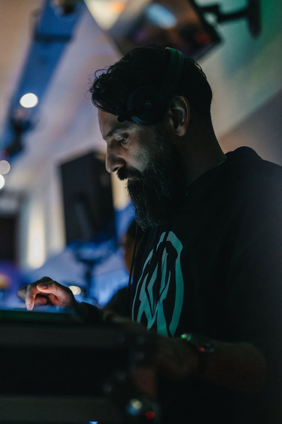 Portrait of Alter Melego in profile, headphones on, lit by the booth